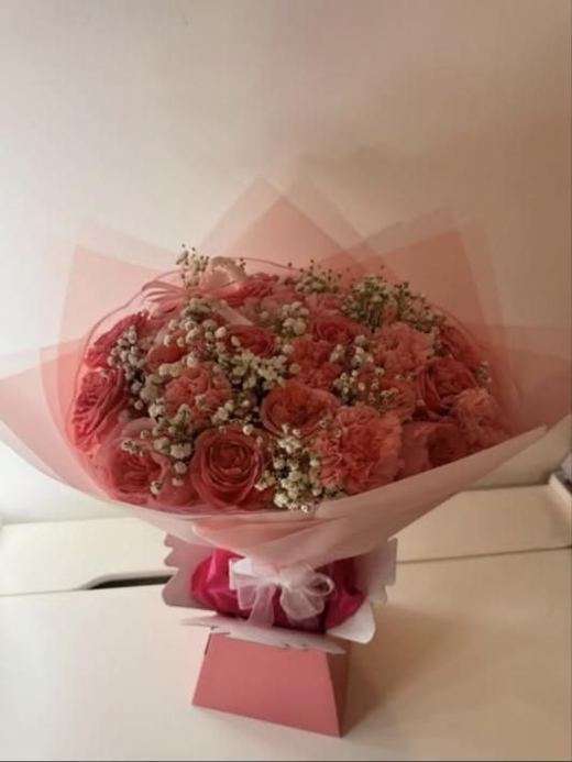 Coral roses and carnations with gypsophila standing in a pink gift box