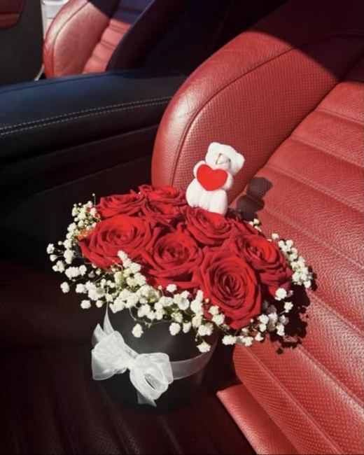Red roses and gypsophila in a black flower box with a white bow and a small teddy