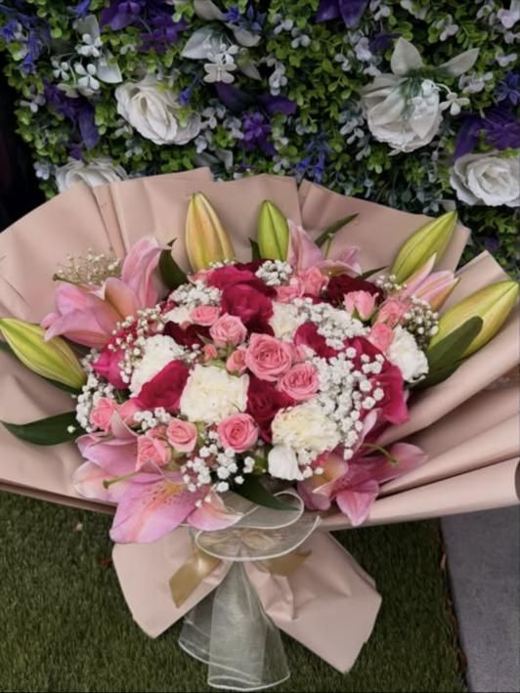 Pink lilies, roses and white carnations with gypsophila in blush wrap