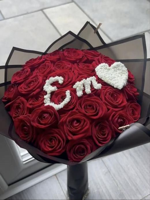 Red roses in black wrap with the initials Em and a heart in gypsophila